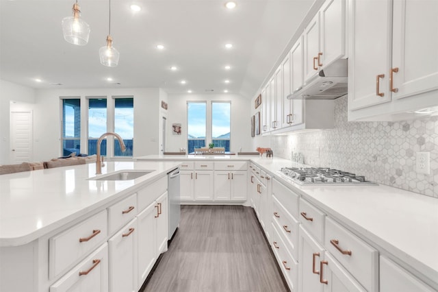 kitchen featuring white cabinets, stainless steel appliances, hanging light fixtures, decorative backsplash, and sink