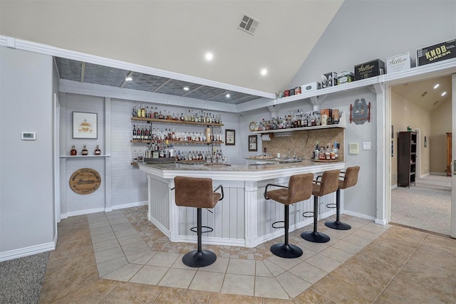 bar featuring light tile patterned floors and vaulted ceiling