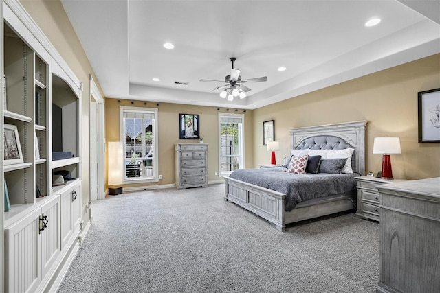 bedroom with carpet floors, a raised ceiling, and ceiling fan