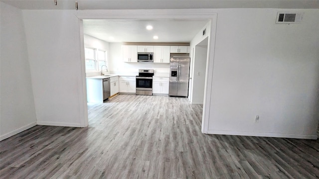 kitchen with light wood-style flooring, a sink, visible vents, white cabinetry, and appliances with stainless steel finishes