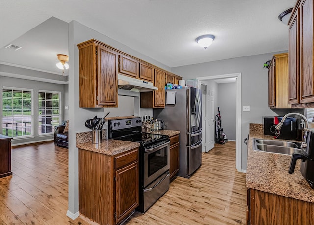 kitchen featuring light stone countertops, light wood-type flooring, stainless steel appliances, and sink