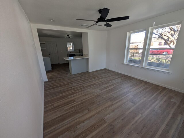 unfurnished living room with ceiling fan and dark wood-type flooring