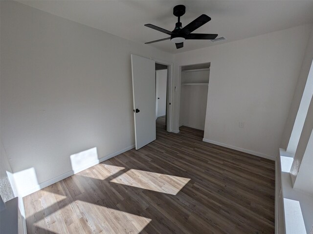 unfurnished bedroom with ceiling fan, a closet, and dark wood-type flooring