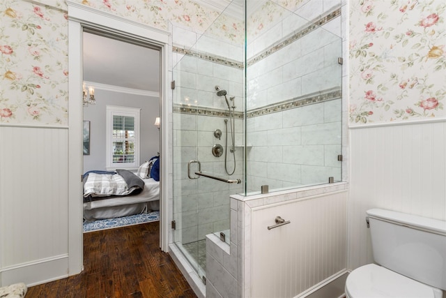 bathroom featuring hardwood / wood-style floors, toilet, a shower with door, and crown molding