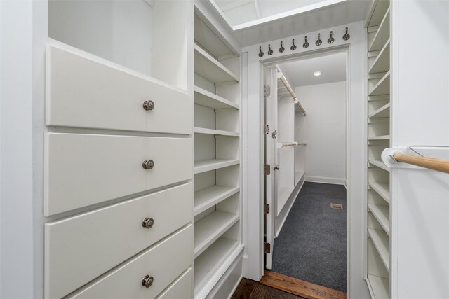 walk in closet with dark carpet