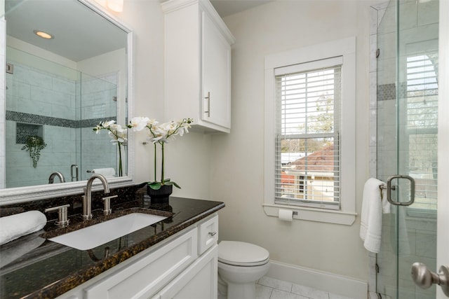 bathroom featuring tile patterned flooring, vanity, toilet, and walk in shower