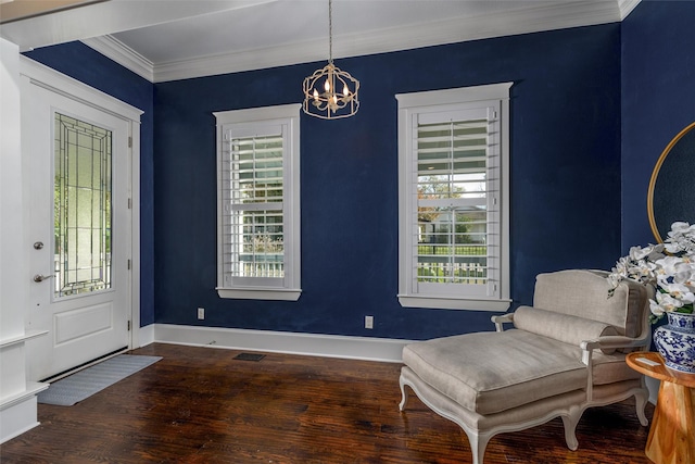 living area featuring dark hardwood / wood-style floors, a healthy amount of sunlight, crown molding, and a chandelier