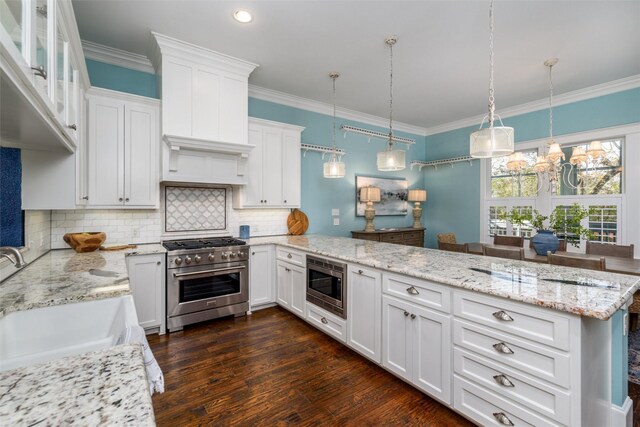 kitchen featuring white cabinets, appliances with stainless steel finishes, hanging light fixtures, and dark wood-type flooring