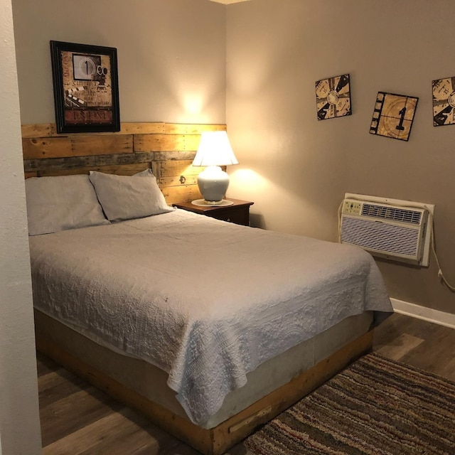 bedroom featuring a wall unit AC and dark hardwood / wood-style flooring