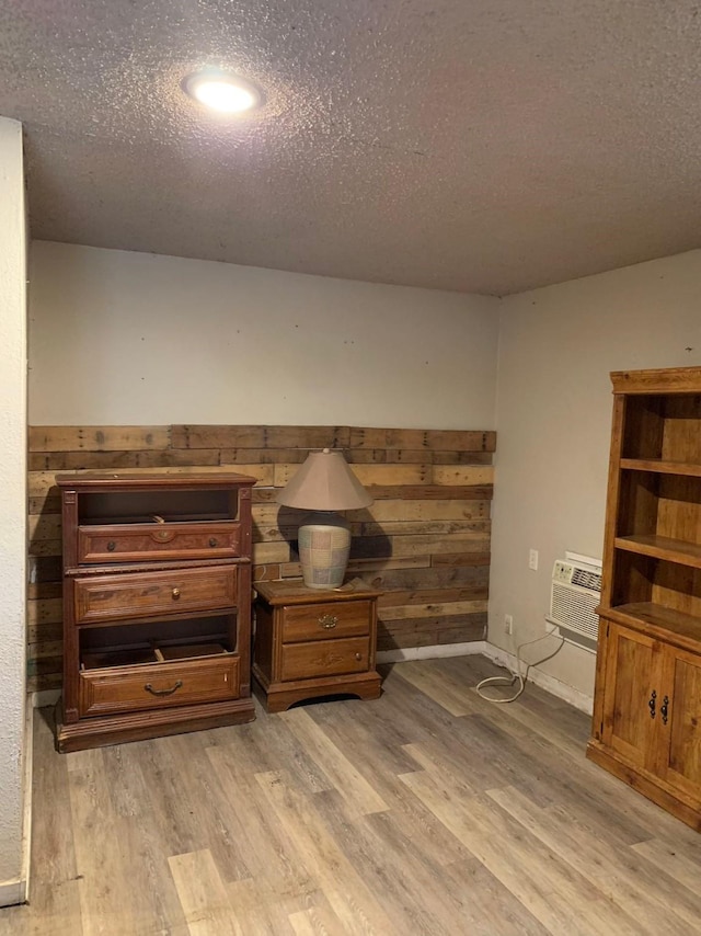 interior space with a wall mounted AC, wood walls, hardwood / wood-style floors, and a textured ceiling