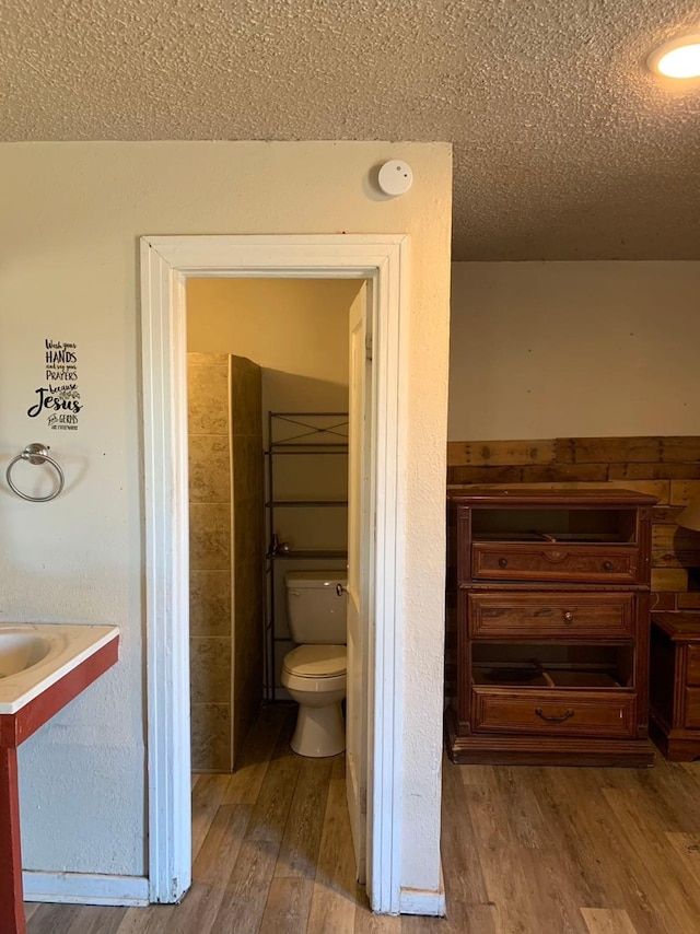 bathroom with vanity, a textured ceiling, hardwood / wood-style flooring, and toilet