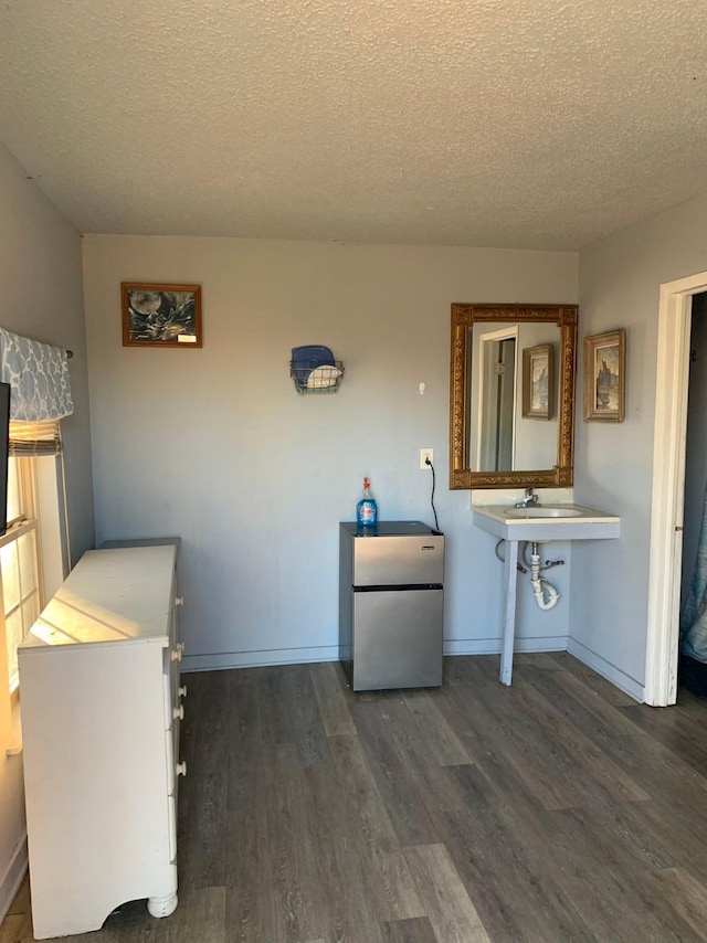 laundry area with a textured ceiling and dark hardwood / wood-style flooring