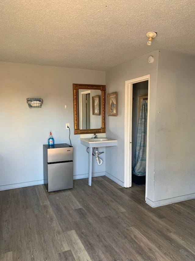 laundry area with a textured ceiling, sink, and dark wood-type flooring