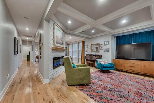 living room with a large fireplace, light hardwood / wood-style floors, beam ceiling, and coffered ceiling