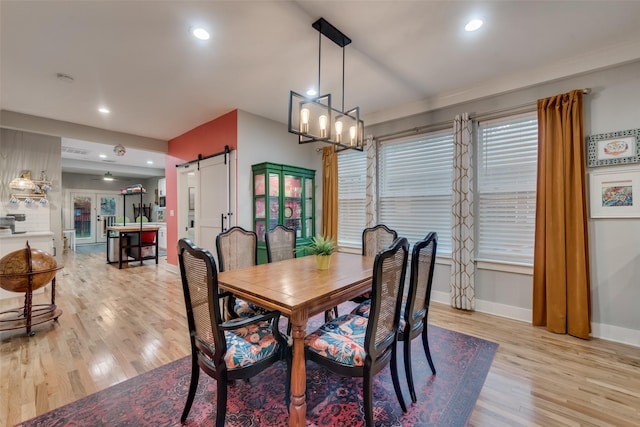 dining room with a barn door and light hardwood / wood-style floors