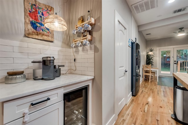 kitchen featuring backsplash, white cabinets, wine cooler, stainless steel fridge, and light hardwood / wood-style floors