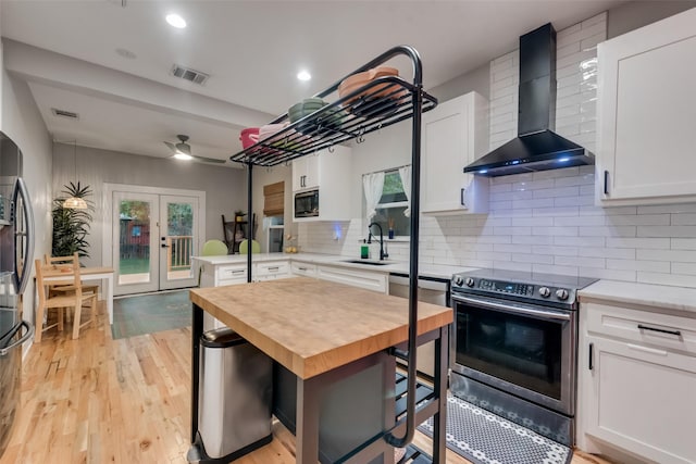 kitchen with wall chimney exhaust hood, white cabinetry, and appliances with stainless steel finishes