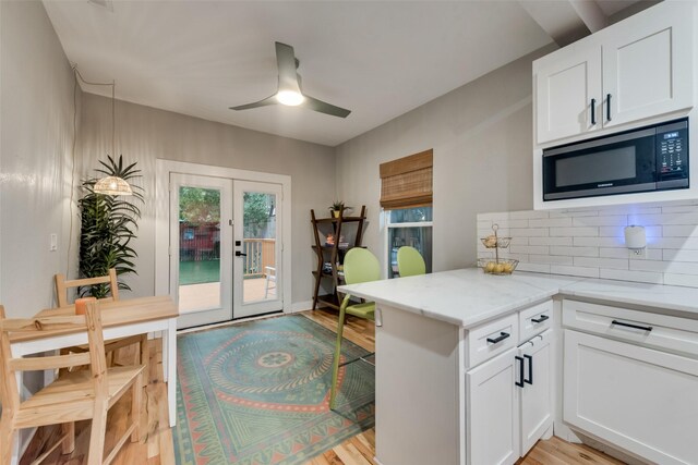 kitchen with white cabinets, wall chimney range hood, sink, light hardwood / wood-style floors, and stainless steel appliances