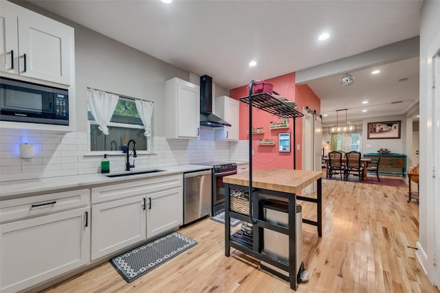 kitchen featuring white cabinets, sink, wall chimney exhaust hood, and appliances with stainless steel finishes