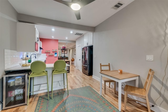 kitchen with white cabinetry, stainless steel fridge with ice dispenser, light hardwood / wood-style flooring, and tasteful backsplash