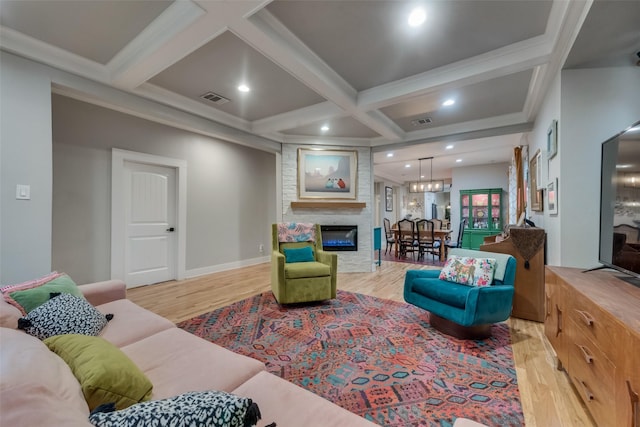 living room featuring beam ceiling, light hardwood / wood-style floors, a fireplace, and coffered ceiling