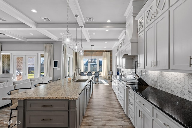 kitchen featuring a large island with sink, a breakfast bar, beamed ceiling, and sink