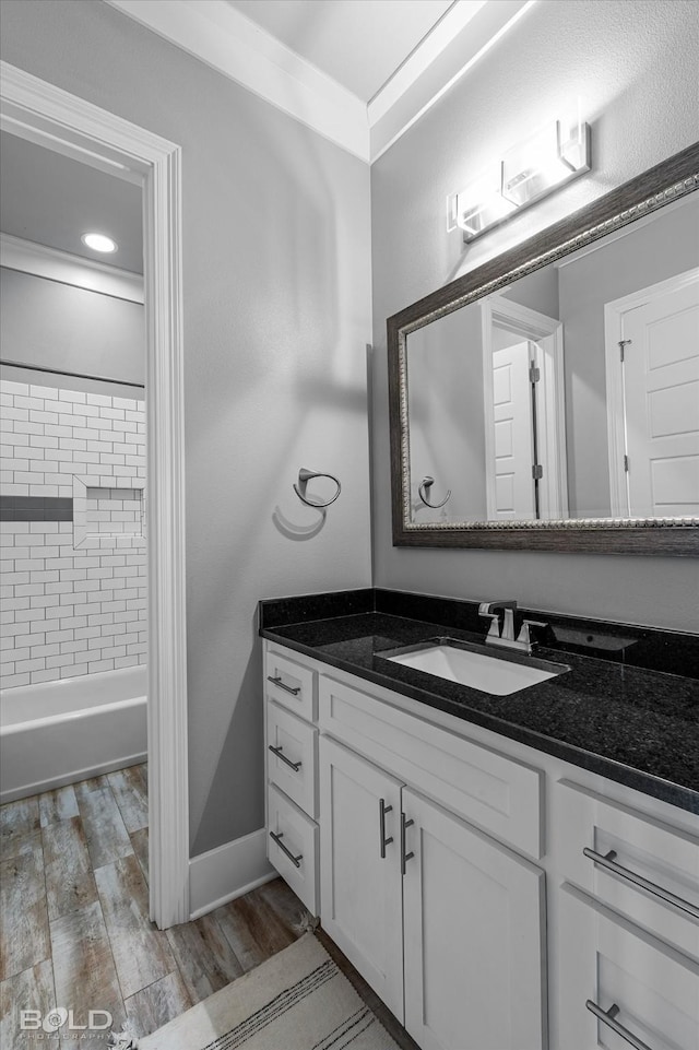 bathroom featuring wood-type flooring, ornamental molding, vanity, and tiled shower / bath