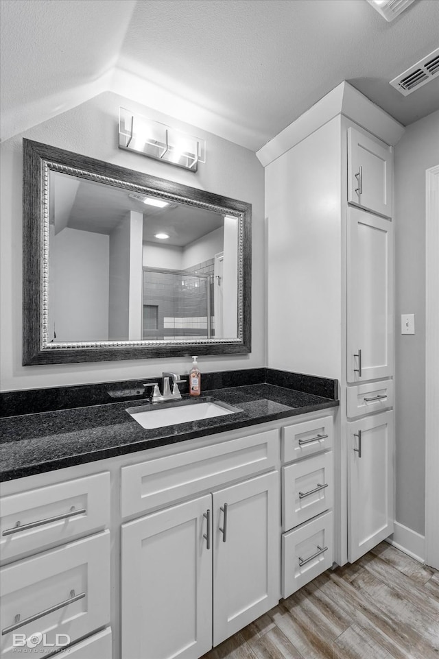 bathroom featuring wood-type flooring, vanity, a textured ceiling, and an enclosed shower