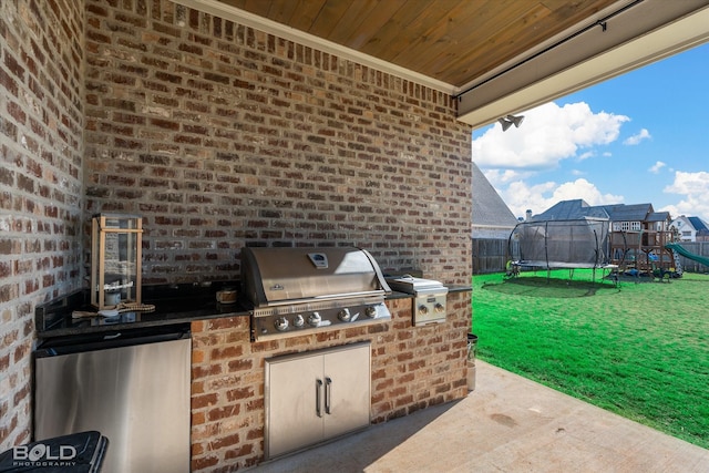 view of patio / terrace with a trampoline, grilling area, a playground, and an outdoor kitchen