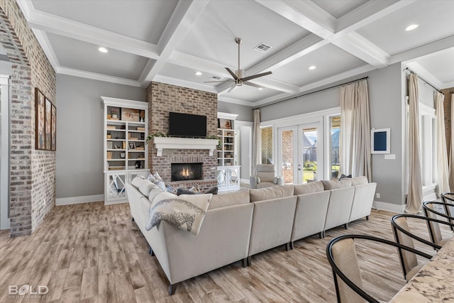 living room with beamed ceiling, a brick fireplace, coffered ceiling, and light hardwood / wood-style floors