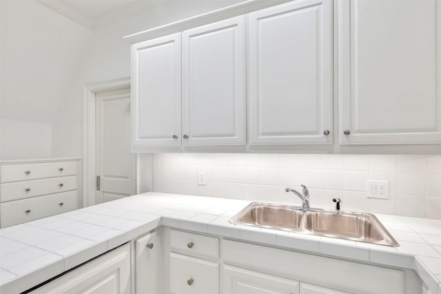 kitchen featuring decorative backsplash, tile countertops, white cabinetry, and sink