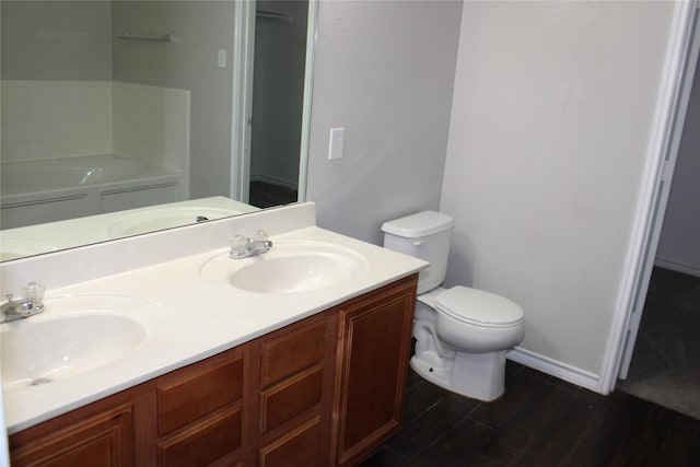 bathroom with a washtub, vanity, hardwood / wood-style flooring, and toilet