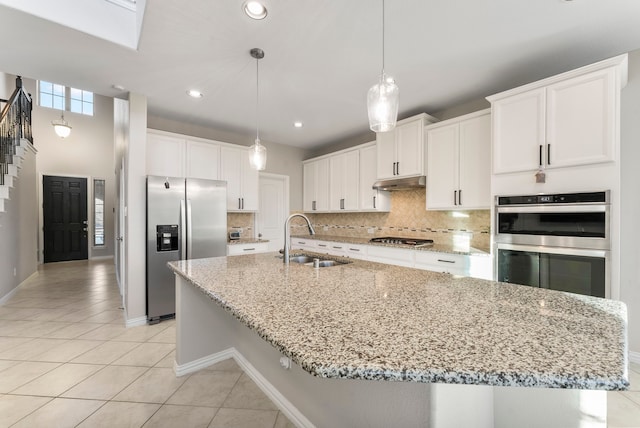 kitchen featuring sink, white cabinets, stainless steel appliances, and decorative light fixtures