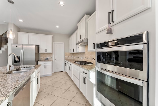 kitchen featuring sink, hanging light fixtures, stainless steel appliances, light tile patterned floors, and white cabinets