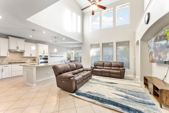 living room with ceiling fan, light tile patterned flooring, and a high ceiling