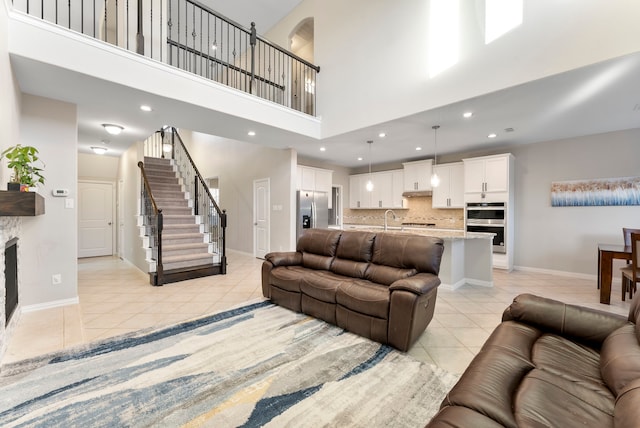 tiled living room featuring a fireplace, sink, and a high ceiling