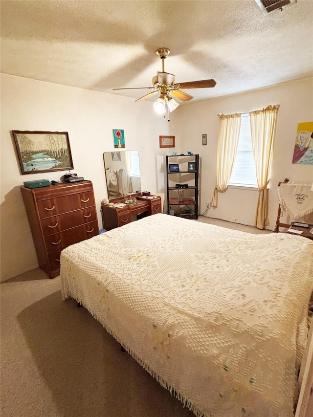 bedroom with ceiling fan, carpet floors, and a textured ceiling