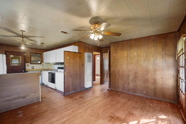 kitchen with wooden walls, white cabinets, ceiling fan, white appliances, and light hardwood / wood-style flooring