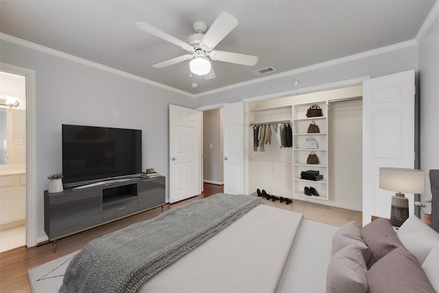 bedroom with ceiling fan, connected bathroom, wood-type flooring, ornamental molding, and a closet