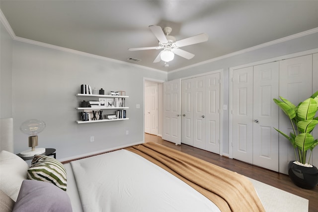 bedroom with ceiling fan, crown molding, dark wood-type flooring, and multiple closets