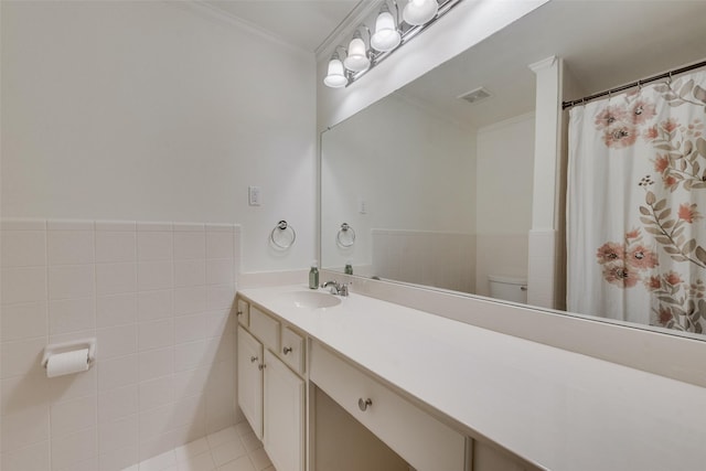 bathroom with tile patterned floors, toilet, vanity, tile walls, and ornamental molding