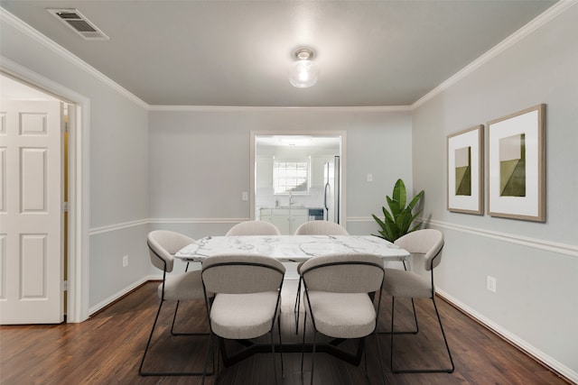 dining room featuring sink, dark hardwood / wood-style floors, and ornamental molding