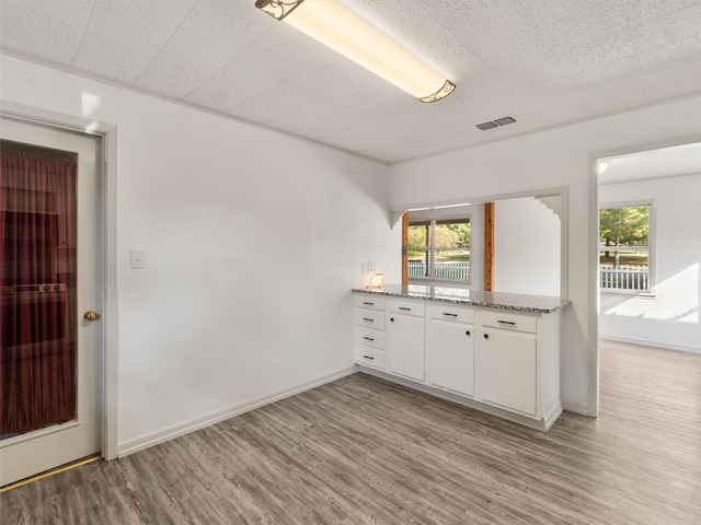 kitchen featuring white cabinetry, light hardwood / wood-style flooring, and light stone countertops