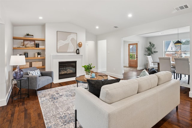 living room with visible vents, dark wood finished floors, a glass covered fireplace, vaulted ceiling, and recessed lighting