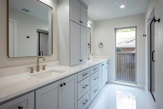 bathroom featuring double vanity, an enclosed shower, a sink, and visible vents