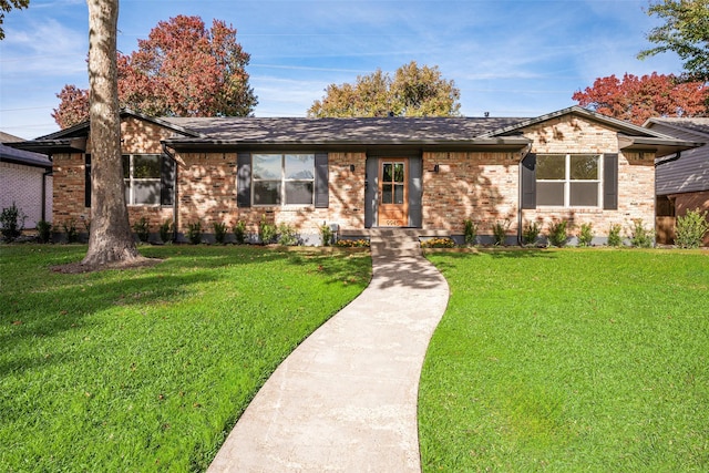 view of front of house with brick siding, roof with shingles, and a front yard