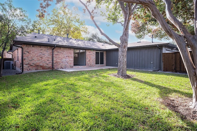 rear view of house with a yard, fence, central AC, and brick siding