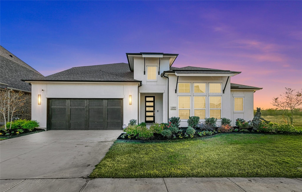 contemporary home featuring a lawn and a garage