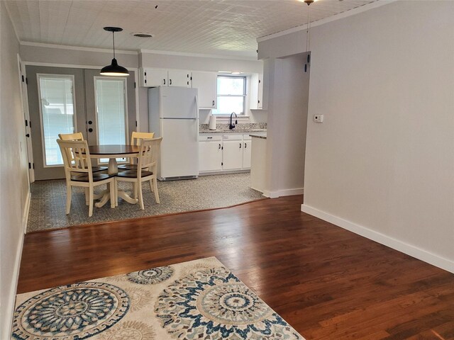 dining space featuring sink, dark wood-type flooring, and ornamental molding