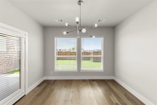 1347 Overton St, Frisco, TX 75036 - unfurnished dining area with a chandelier, wood finished floors, and baseboards